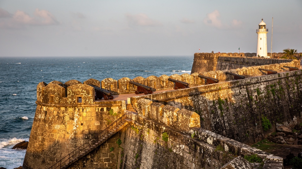 Massive stone ramparts of Diu Fort with a lighthouse over the sea